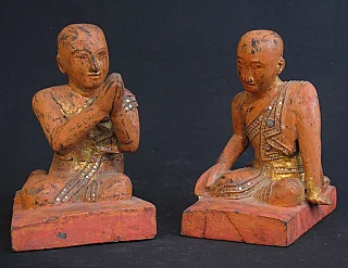Set of Burmese wooden monk statues, seated on red bases, front view with namaskara mudra