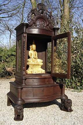 Houten Birmese tempel met open glazen deur en zichtbaar zittend beeld in de nis