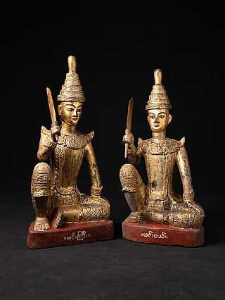 Pair of antique Burmese Nat statues in wood, seated on red bases, front view