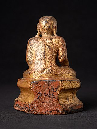 Wooden monk statue from Burma, rear view with worn surface and dark markings on the base