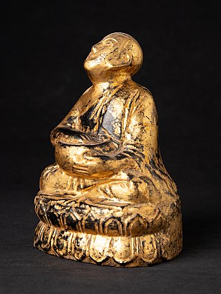 Burmese wooden monk statue with worn gilt surface, three-quarter left view