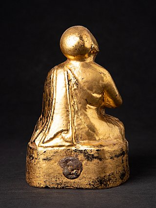 Burmese wooden monk statue showing robe folds, rear view