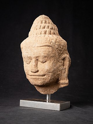 Boeddhahoofd uit Cambodja in driekwartaanzicht, glimlach en haarlokken zichtbaar