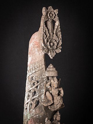 Upper detail of the wooden temple panel, showing the floral crest and carved figure