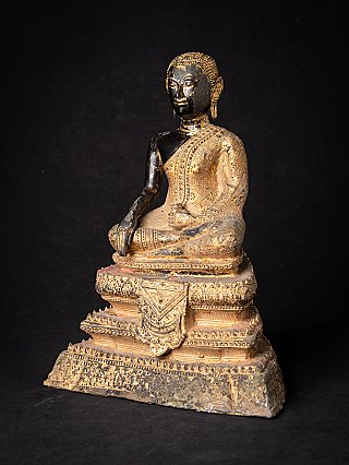 Thai bronze monk statue seated on a tiered base, three-quarter view showing robe pattern