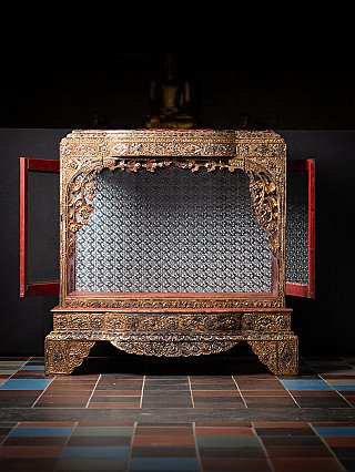 Burmese wooden temple shrine with open red side doors and mirrored interior back