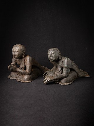Burmese bronze monk statues seated on the ground, three-quarter view
