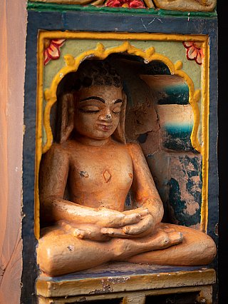Detail van het zittende Jain-beeld in de nis met de handen in dhyana mudra en zichtbare verfresten