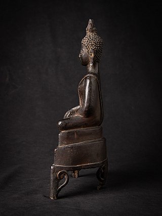 Thai bronze Buddha statue in side profile, seated on a tall stepped base