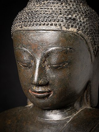 Close-up face detail of the Burmese bronze Buddha, showing patina and wear