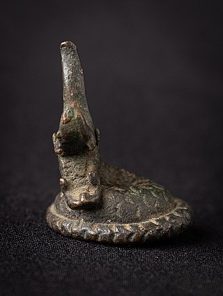 Bronze opium weight from Burma, front view of the head with upright horn-like fin