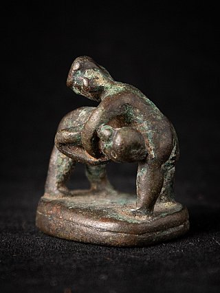 Antique bronze opium weight from Myanmar showing a figure draped over another, angled front view