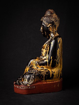 Burmese wooden Buddha statue in left side profile with black lacquer and gilding traces