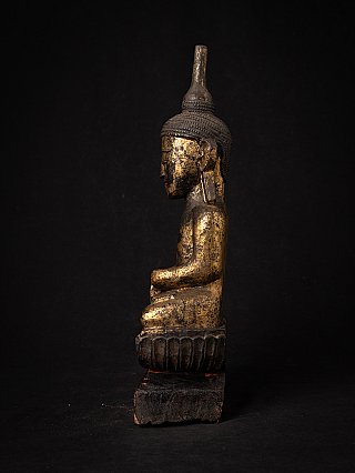 Antique wooden Buddha statue in side profile, showing the tall ushnisha