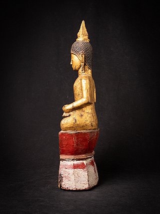 Wooden Buddha statue from Laos on a red and white base, left side profile