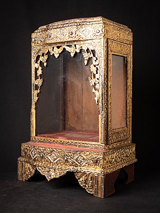 Antique wooden Burmese Buddha temple, three-quarter view showing the glass side panel