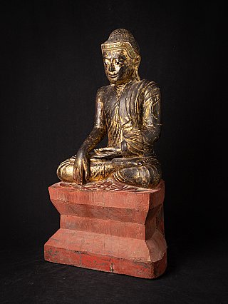 Wooden Buddha statue from Myanmar, three-quarter view showing worn gilding and red base