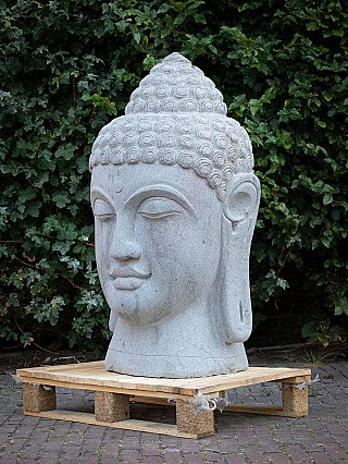 Boeddhahoofd van andesietsteen uit Indonesië in driekwartaanzicht links, op pallet