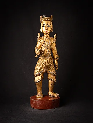 Burmese Nat statue in wood on a red base, standing with a sword, full-front view