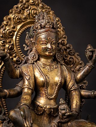 Vasudhara face detail in gilt bronze, showing crown, earrings and halo scrollwork
