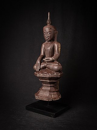 Burmese wooden Buddha statue in three-quarter view, seated on stepped base