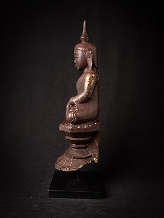 Wooden Burmese Buddha statue in side profile, seated posture with elongated earlobes