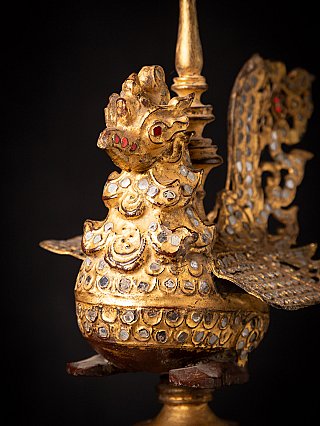 Side close-up of the gilded bird finial with inset glass and wing detail