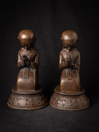 Burmese bronze monk statues on lotus bases, frontal view with praying hands