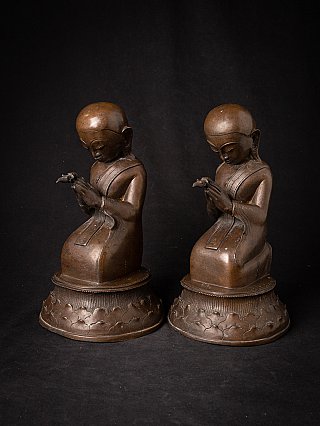 Burmese bronze monk statues seated, three-quarter view highlighting the joined hands