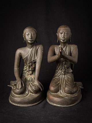 Two seated Burmese bronze monk statues, frontal view showing robe folds and patina