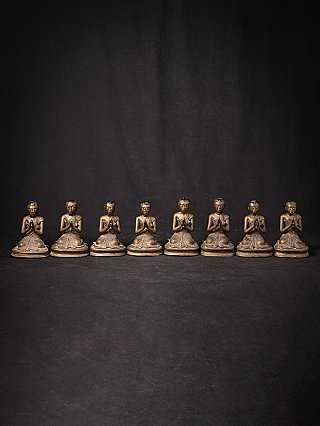 Group view of eight seated Burmese bronze monk statues, straight-on front view