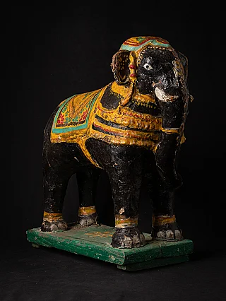 Antique Indian elephant statue in three-quarter view with painted blanket and green base