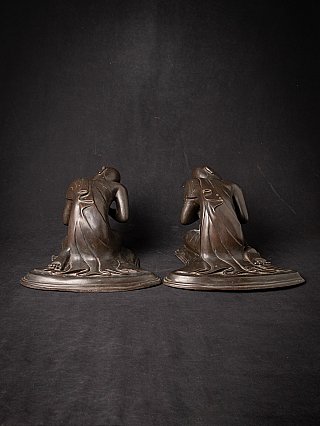 Rear view of the pair of Burmese bronze monk statues showing robe folds over the bases