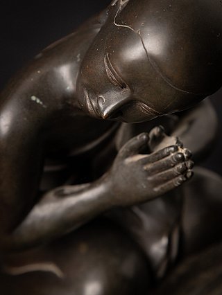 Face and hands detail of a Burmese bronze monk statue in namaskara mudra