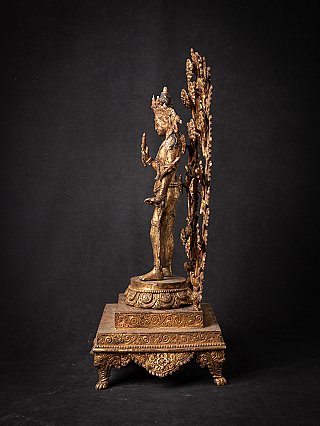 Nepali bronze Lokeshwor statue in side profile with raised hand and tall floral aureole