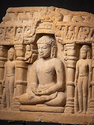Zittende figuur in het Jain-steenfragment, driekwartaanzicht met pijlers en nevenfiguren