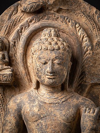 Nahaufnahme von Gesicht und Brust der Buddha-Statue mit Lockenhaar und Nimbus im Relief