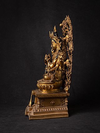 Nepali bronze Manjushri statue seated on base, left side profile with halo