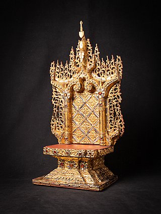 Wooden throne from Burma, three-quarter view showing openwork gilded back and red seat