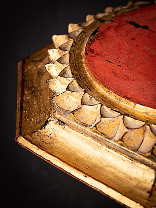 Lotus rim and red top surface detail on the gilded wooden Buddha stand