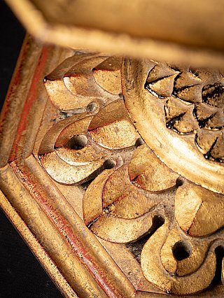 Close-up of gilt wood carving with floral and lotus forms on the lower rim