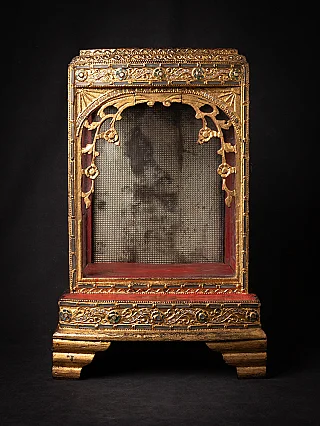 Antique Burmese wooden Buddha temple shrine, front view with gilded arch and red interior