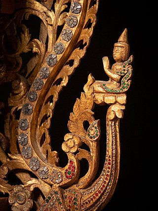 Side ornament detail showing a small seated figure on gilded scrollwork with inlay