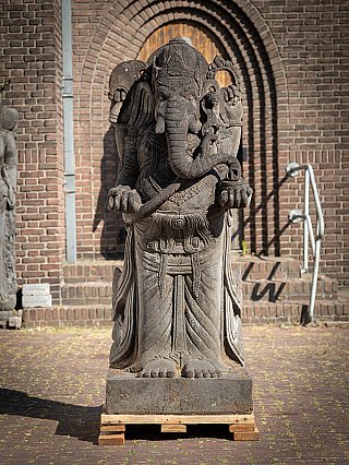 Lavastenen Ganesha-beeld uit Indonesië, staand op sokkel, frontaal gefotografeerd
