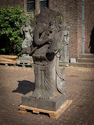 Ganesha-beeld in lavasteen, driekwartaanzicht links met zicht op sokkel en armen