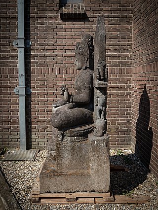 Avalokiteshvara statue in lavastone from Indonesia, seated, left side profile with tall back slab