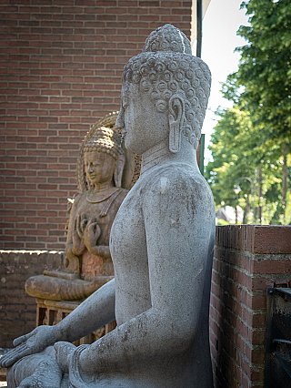 Groot lavastenen Boeddhabeeld, Indonesië, zijaanzicht met oor en arm in zittende houding