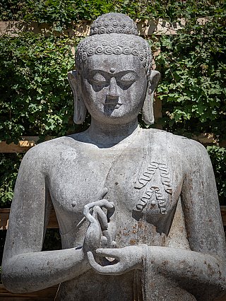 Detail van hoofd en handen van de lavastenen Boeddha, dharmachakra mudra van voren