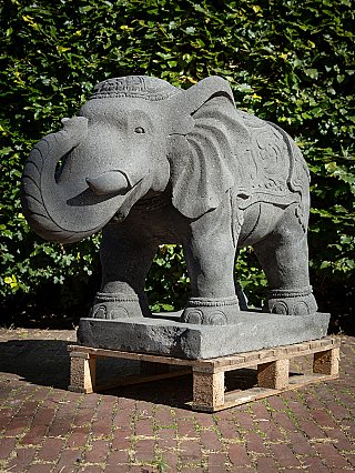 Lavastone elephant statue from Indonesia, three-quarter view with curled trunk on base