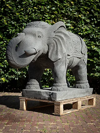 Lavastone elephant statue from Indonesia, three-quarter view with curled trunk on base